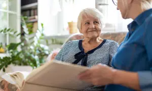 Starsza pani z uśmiechem słucha opowieści o tym, czym jest demencja. Wspólne przeglądanie albumu buduje więź.