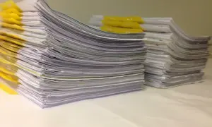 Stosy dokumentów, żółte zakładki. Orzeczenie o potrzebie kształcenia specjalnego otwiera drogę do wsparcia edukacyjnego.