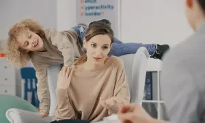 Matka rozmawia z terapeutą o różnych rodzajach ADHD, podczas gdy jej syn z nadpobudliwością bawi się za jej plecami.