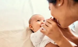 Mama czule całuje swoje dziecko, które wpatruje się w nią z zaciekawieniem. Może to być sygnał, że dziecko nie reaguje na imię, ale miłość mamy jest dla niego najważniejsza.