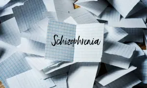 Rozrzucone kartki w kratkę, na jednej napis "Schizophrenia". Symbol chaosu myśli, jak w schizofrenii hebefrenicznej.