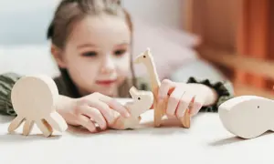 Dziecko bawi się drewnianymi zwierzątkami, co może być formą maskowania autyzm.