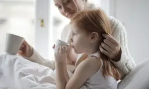 Ciepły uścisk mamy, gdy dziecko z autyzmem pije z kubeczka.