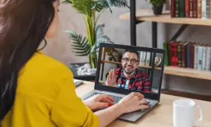 Kobieta na wideo rozmowie z mężczyzną, który uśmiecha się i macha. Może to być konsultacja online, np. test na aspergera.