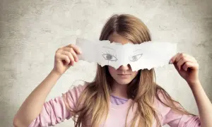 Dziewczynka z rysunkiem oczu na papierze zakrywającym jej twarz. Czy to maskowanie problemów, czy objaw mitomanii?