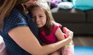 Mała dziewczynka z płaczem tuli się do mamy, przeżywając lęk separacyjny.