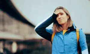 Kobieta z ręką na czole, wyrażająca zmartwienie lub dezorientację, być może z powodu zaburzeń poznawczych.