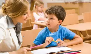 Nauczycielka wspiera chłopca w nauce, pokazując mu, jak rysować. To przykład indywidualnego podejścia w kształceniu specjalnym.