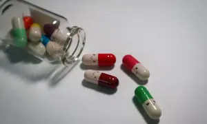 Kolorowe kapsułki, niektóre z uśmiechniętymi buźkami, symbolizują antydepresanty a psychotropy.