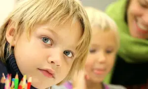 Chłopiec z niebieskimi oczami i blond włosami, obok niego inne dziecko i uśmiechnięta osoba. Jak uspokoić dziecko z Aspergerem?