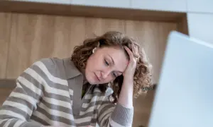 Kobieta z problemami z koncentracją opiera głowę na dłoni, patrząc w dół.