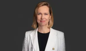 Uśmiechnięta kobieta w białej marynarce, profesjonalny terapeuta autyzmu, gotowa do pomocy.