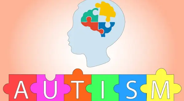 Sylwetka głowy z mózgiem z puzzli, poniżej napis AUTISM ułożony z kolorowych puzzli. Symbolizuje zespół Aspergera.