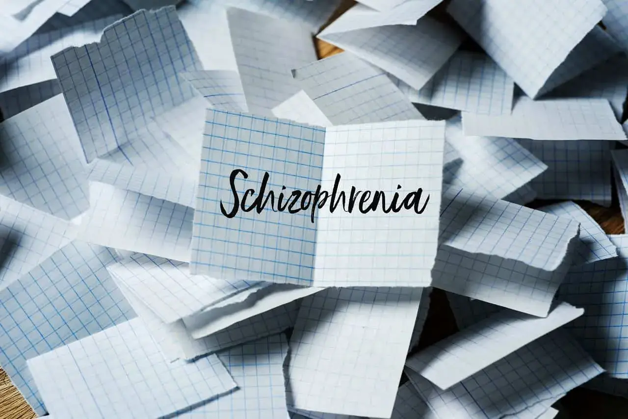 Rozrzucone kartki w kratkę, na jednej napis "Schizophrenia". Symbol chaosu myśli, jak w schizofrenii hebefrenicznej.