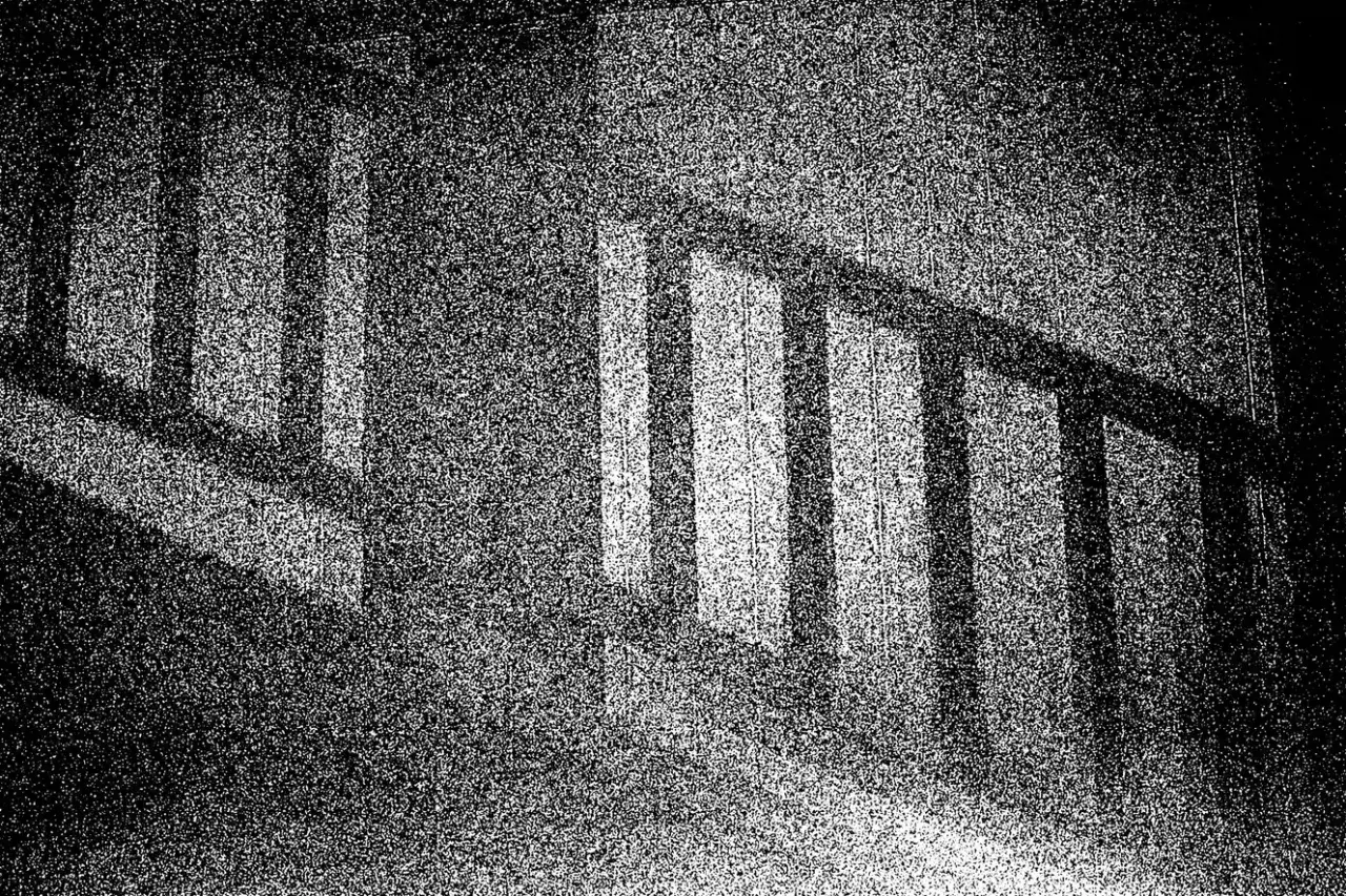 Ciemne pionowe słupki balustrady rzucają cienie, tworząc wrażenie optycznego śniegu na tle.