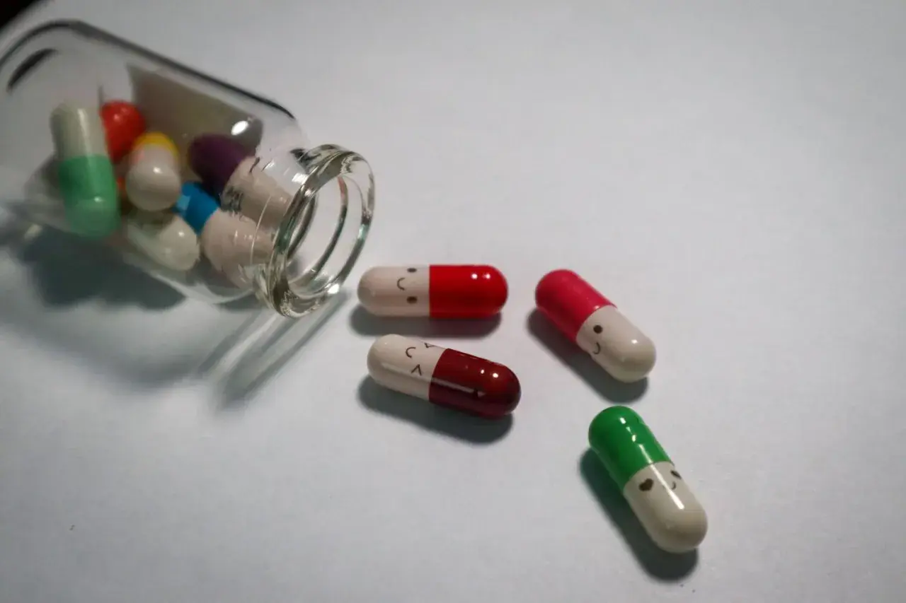 Kolorowe kapsułki, niektóre z uśmiechniętymi buźkami, symbolizują antydepresanty a psychotropy.