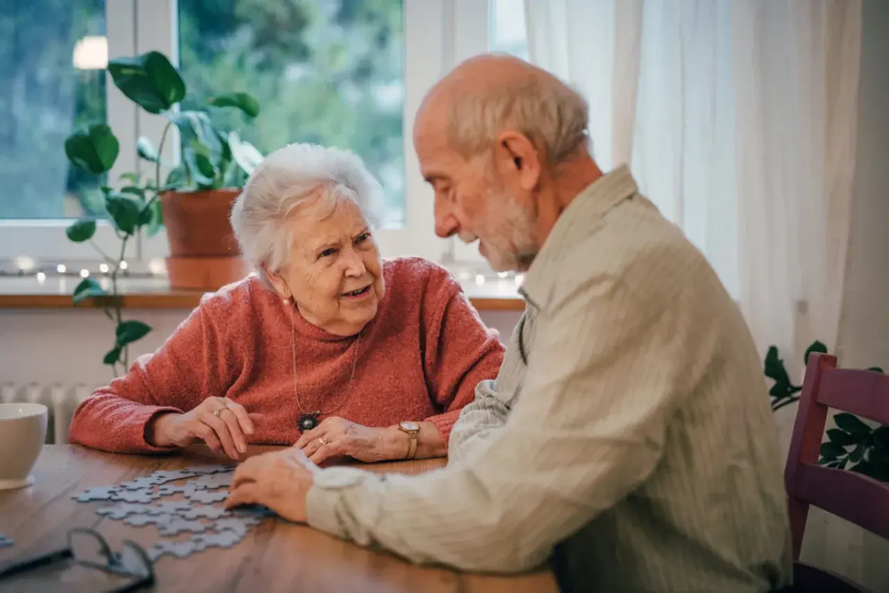Para seniorów układa puzzle, ciesząc się wspólnymi ćwiczeniami umysłowymi.