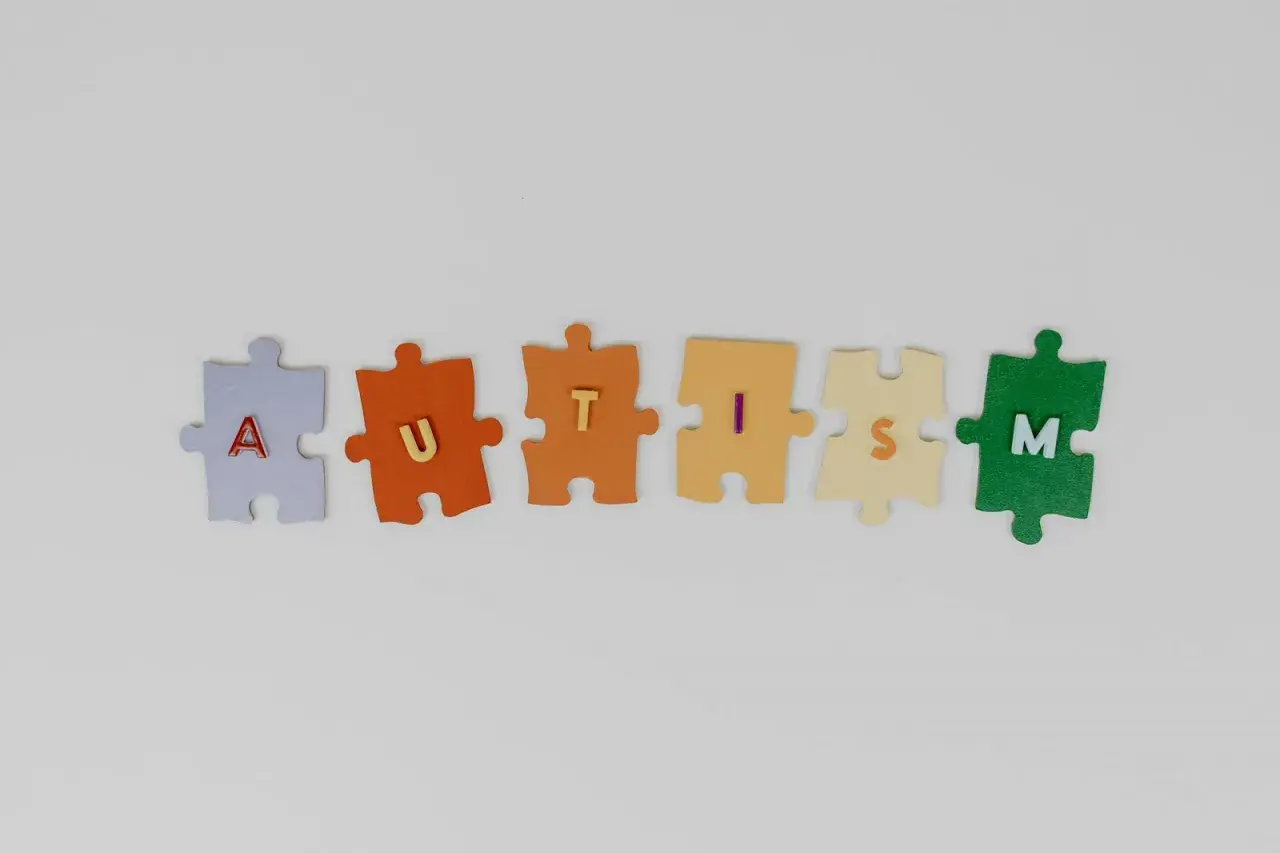 Kolorowe puzzle układają się w napis AUTISM, symbolizując złożoność i różnorodność stopni autyzmu u dzieci.
