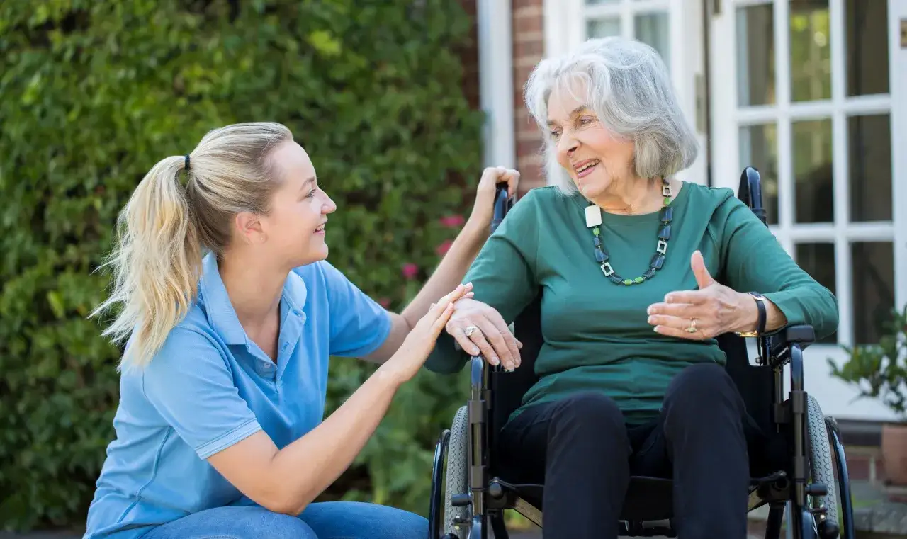 Młoda kobieta wspiera starszą panią na wózku. Pokazuje, jak wytrzymać z chorym na alzheimera, okazując cierpliwość i troskę.