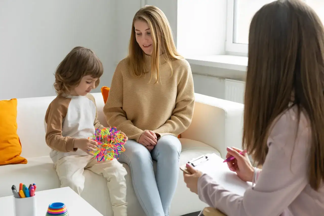 Dziecko z autyzmem bawi się kolorową zabawką podczas sesji terapeutycznej. Długość życia dzieci z autyzmem jest różna, ale wsparcie pomaga im rozwijać się.