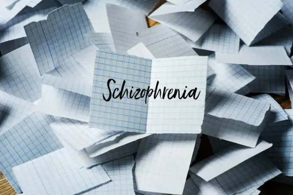 Rozrzucone kartki w kratkę, na jednej napis "Schizophrenia". Symbol chaosu myśli, jak w schizofrenii hebefrenicznej.