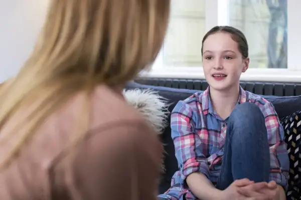 Dziewczynka z autyzmem opowiada o swoich lękach, siedząc na kanapie naprzeciwko terapeuty.