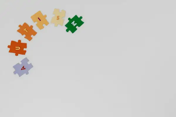 Kolorowe puzzle z literami tworzą napis "AUTYZM". Każdy element symbolizuje unikalność i potrzebę zrozumienia.